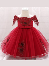 Load image into Gallery viewer, Baby dress has a satin embroidered bodice with pearl details and capped sleeves, a bow belt at the waist, and a tulle skirt with flower applique
